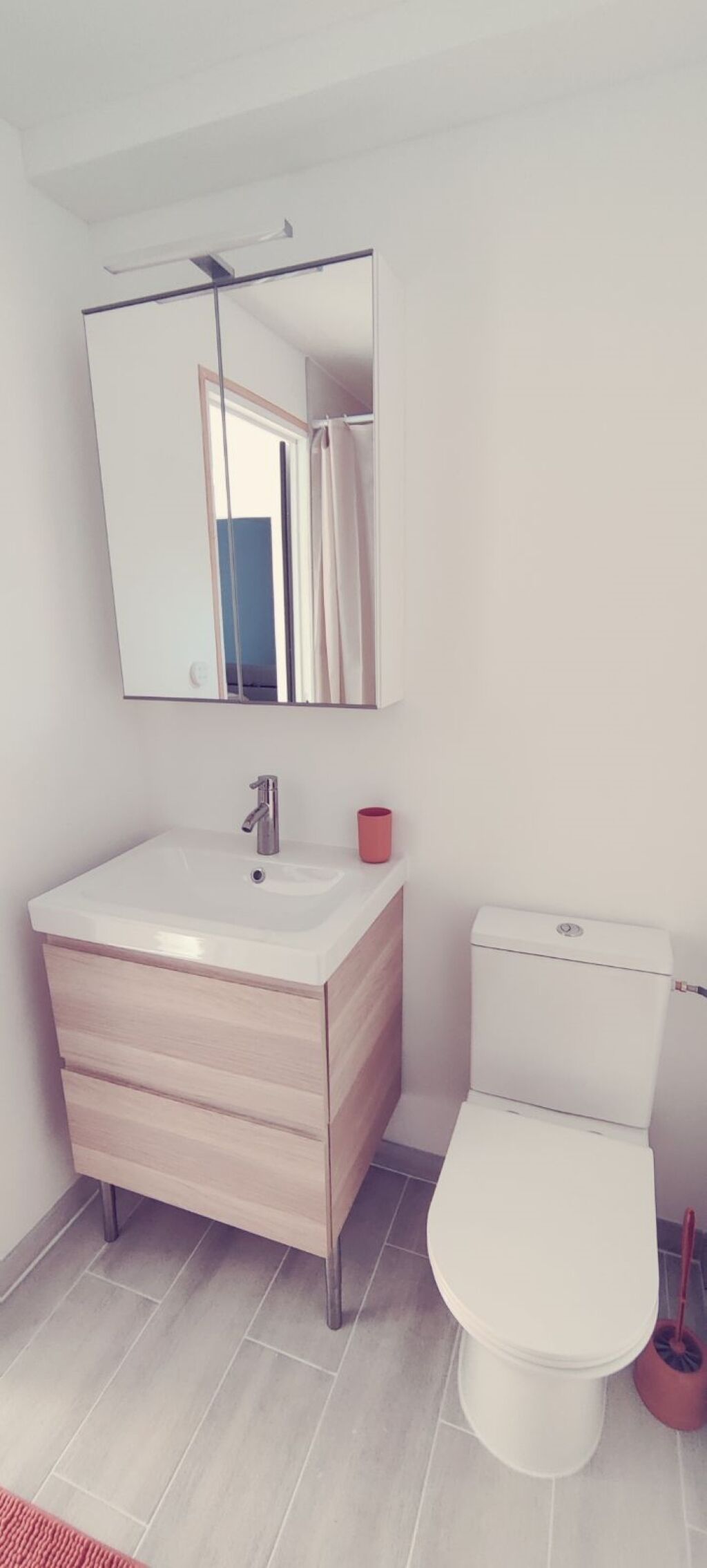 A modern bathroom with a white sink, mirror, and toilet.
