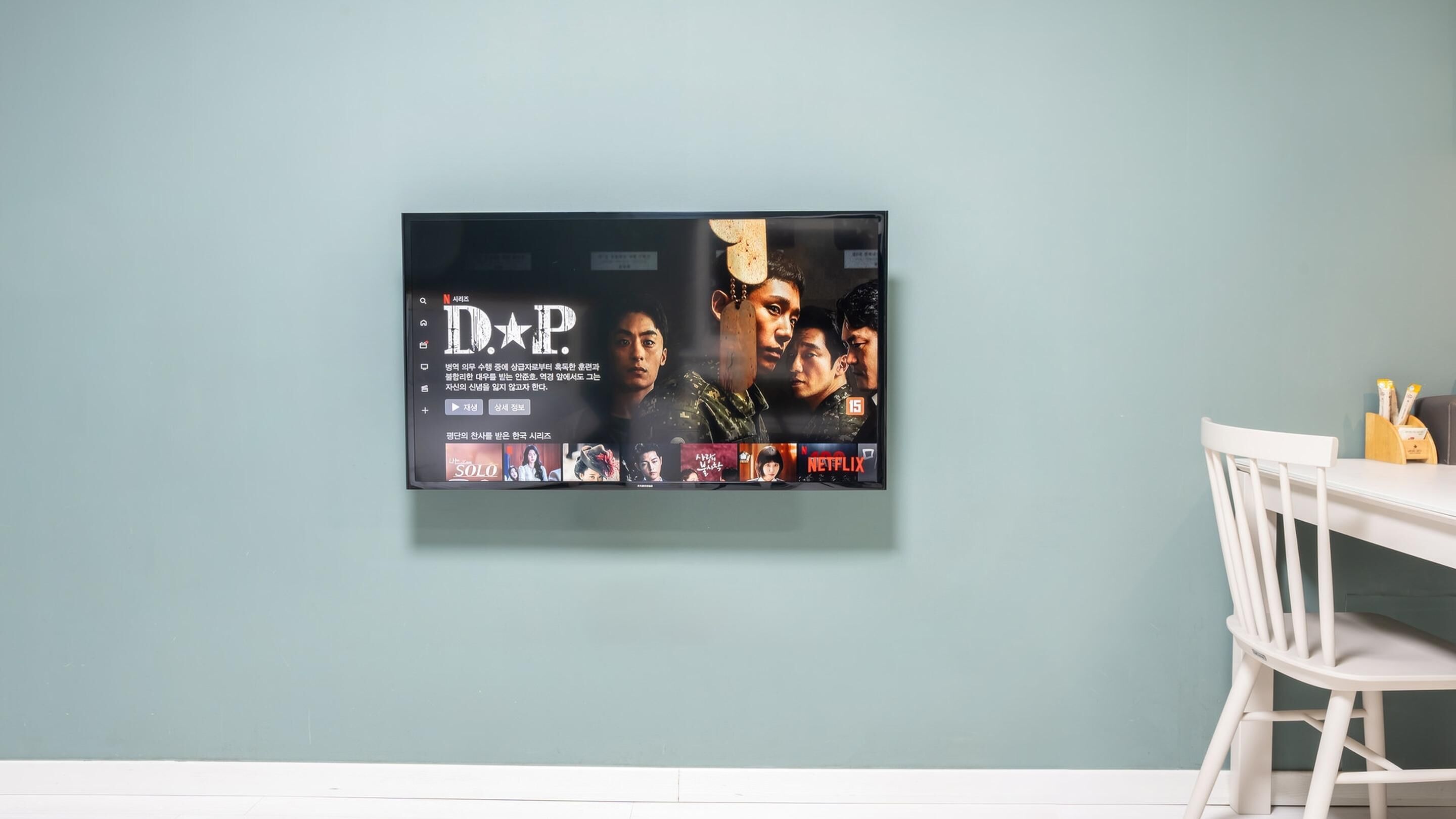 A wall-mounted television displaying a movie poster with Korean text and logos for Netflix and a drama series.