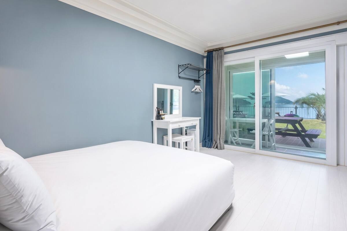 Un dormitorio con cama, escritorio y vistas al exterior a través de una puerta corrediza de vidrio.