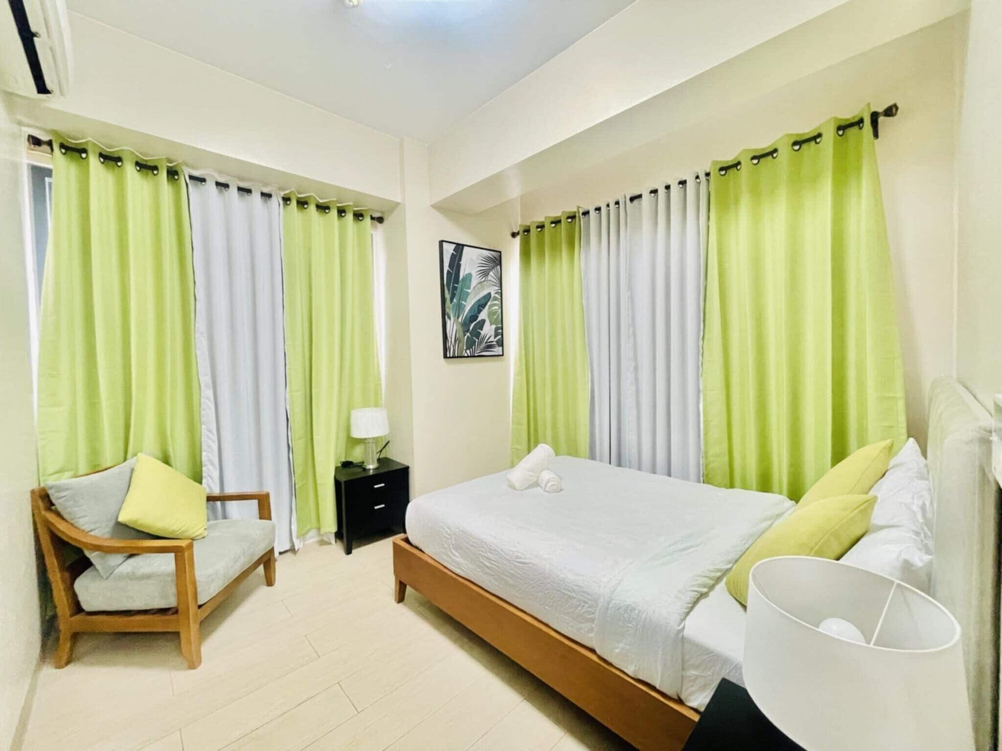 A bedroom with a bed, a chair, a nightstand, and a lamp.