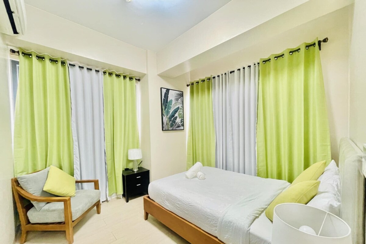 Une chambre à coucher avec un lit, une chaise, une table de chevet et une lampe.