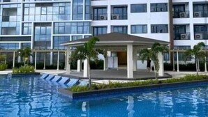 A modern multi-story building with a swimming pool in front. - MACTAN NEWTOWN OMP FAMILY ROOM (Lapu-Lapu)
