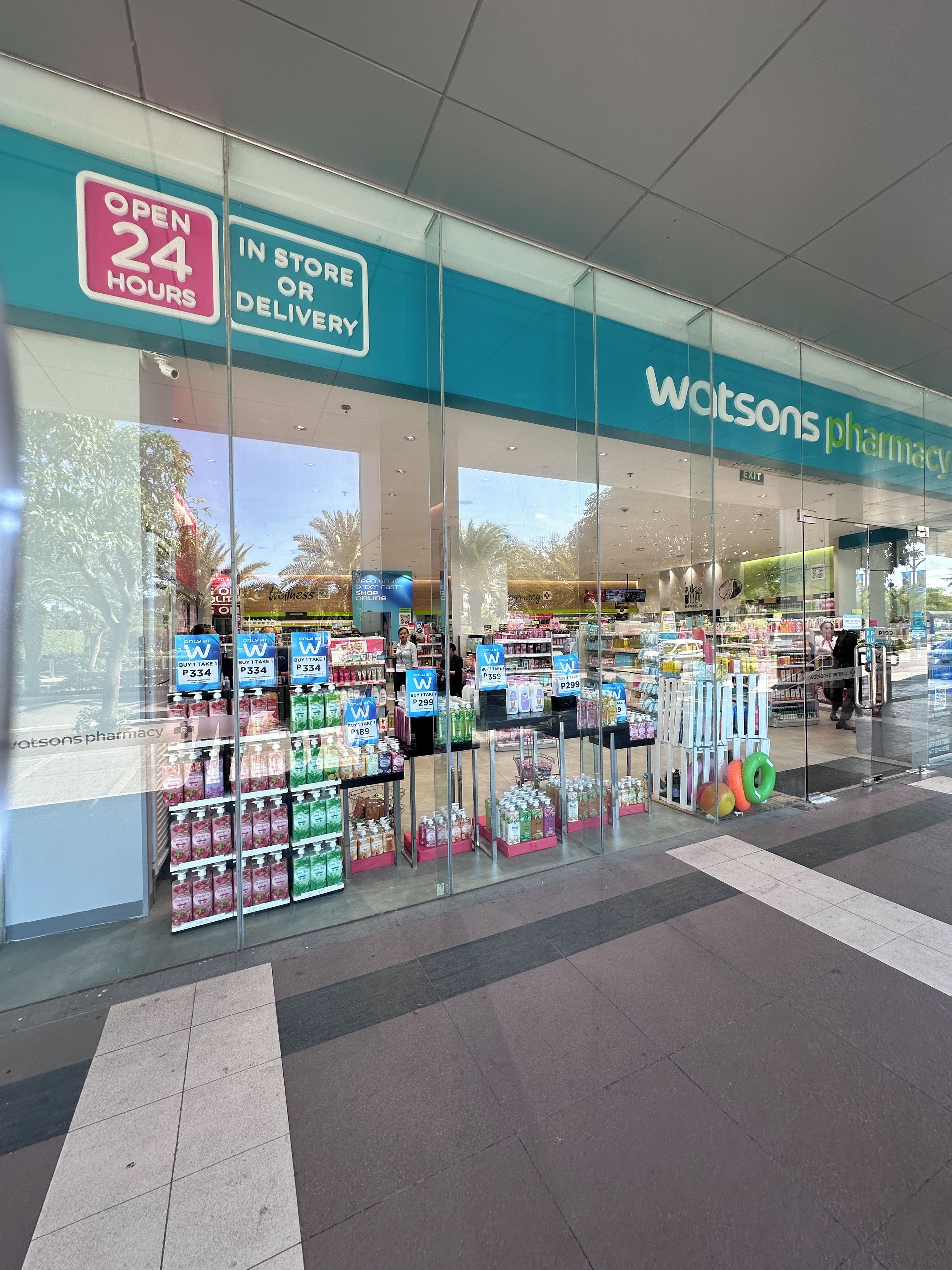 A pharmacy with a 24-hour service sign, a visible entrance, and a variety of products on display.