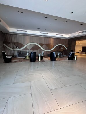 Un hall amplio con diseño moderno, que cuenta con un mostrador de recepción, zona de estar y una pared decorativa.