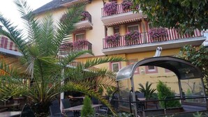 A multi-story building with balconies adorned with flowers, outdoor seating, and a covered area. - Hotel Rüdesheimer Hof (Ruedesheim am Rhein)