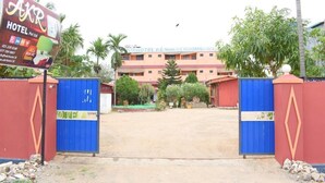 Entrada de un hotel con un letrero, un camino con portones y un edificio al fondo.