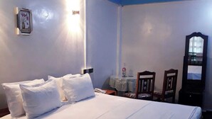 Habitación de hotel con cama, escritorio, silla, espejo y un cuadro en la pared.