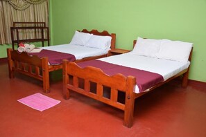 Two wooden beds with white linens and a purple bedspread, a wooden bench, and a green wall. - AKR hotel (Kilinochchi)