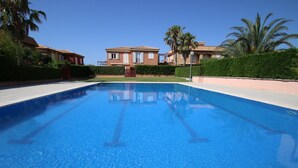 Una piscina con borde de azulejos, rodeada de un paseo empedrado.