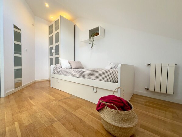 A modern bedroom with a bed, built-in wardrobe, and a radiator.