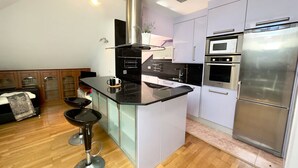 A modern kitchen with a central island, stainless steel appliances, and a bar stool area.