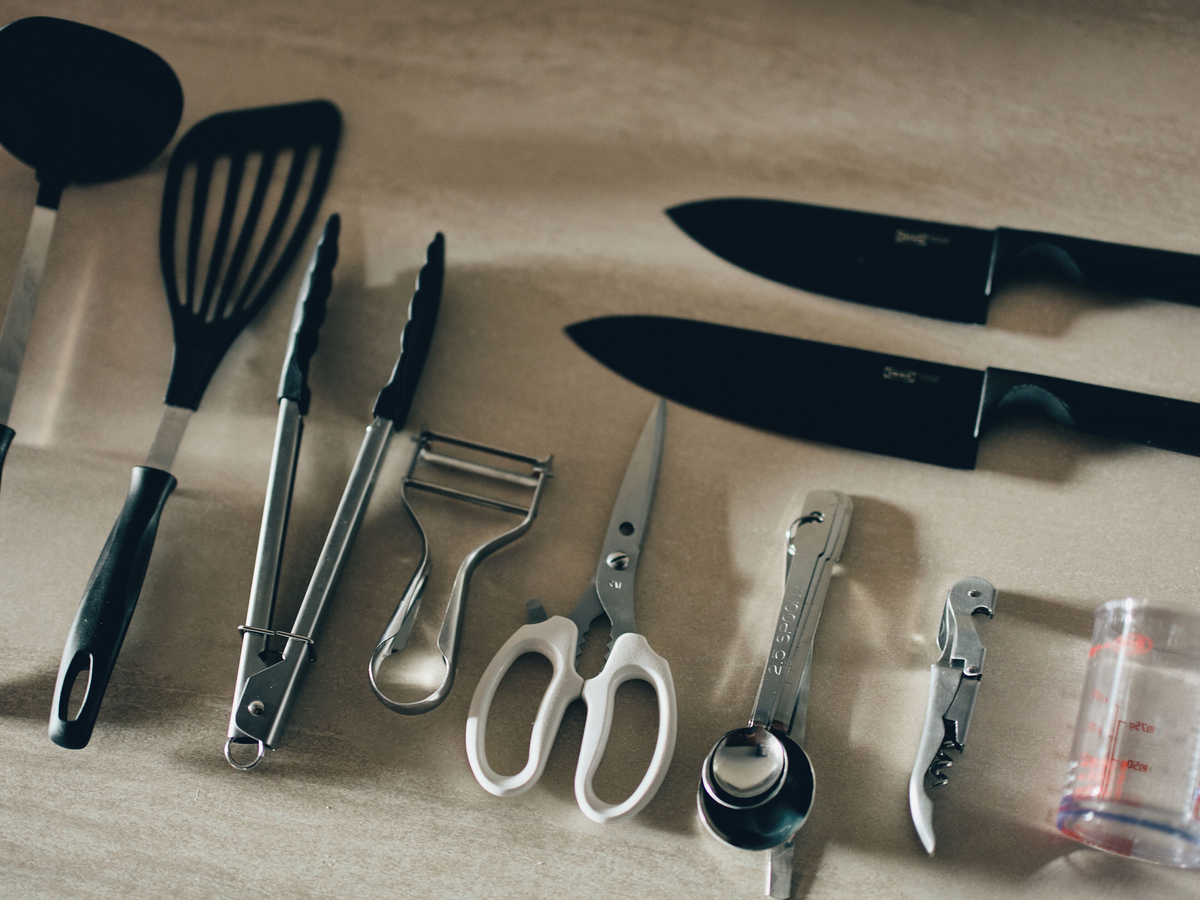 Divers utensílios de cozinha dispostos sobre uma superfície bege.