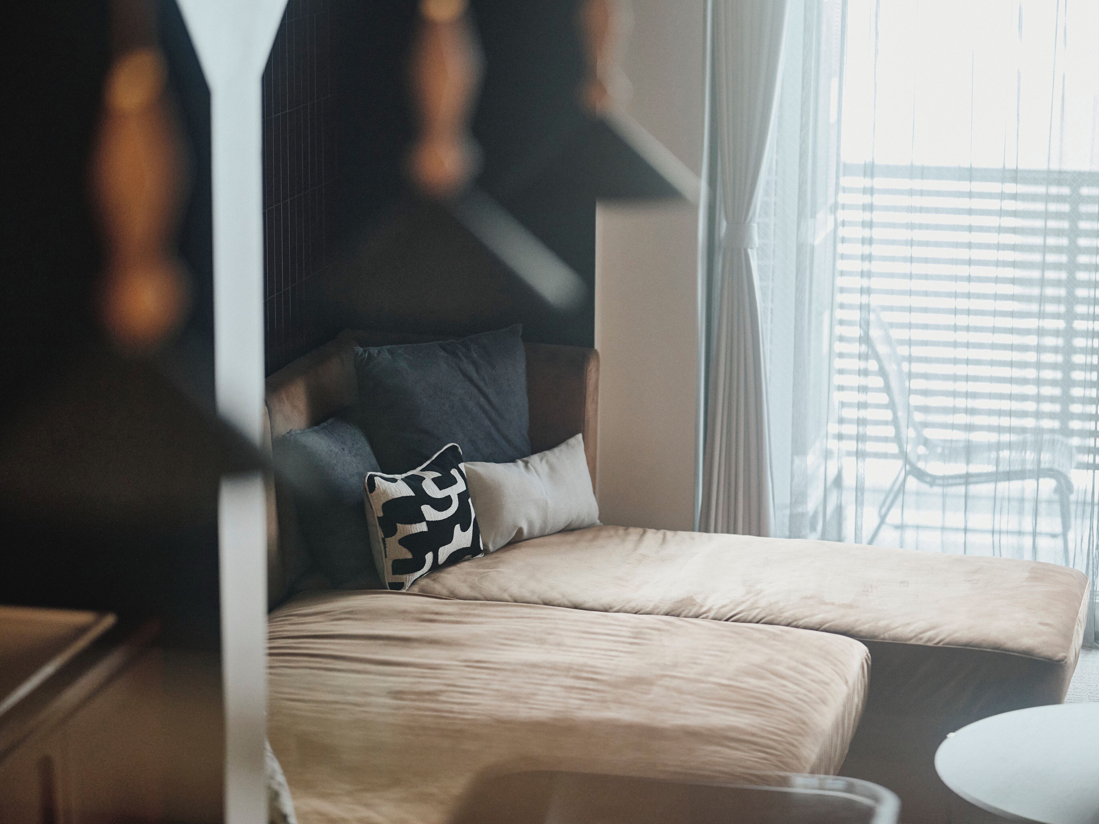 Een moderne slaapkamer met een slaapbank, een klein rond tafeltje en een stoel.