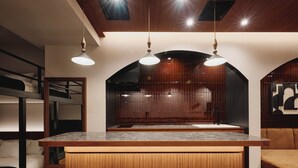 Una cocina moderna con una isla de madera, taburetes negros y luces colgantes.