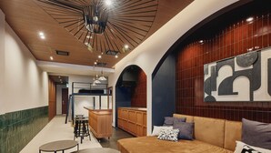 Un interior moderno con techo de madera, una lámpara central, un sofá con cojines, una pequeña mesa redonda y una zona de bar.
