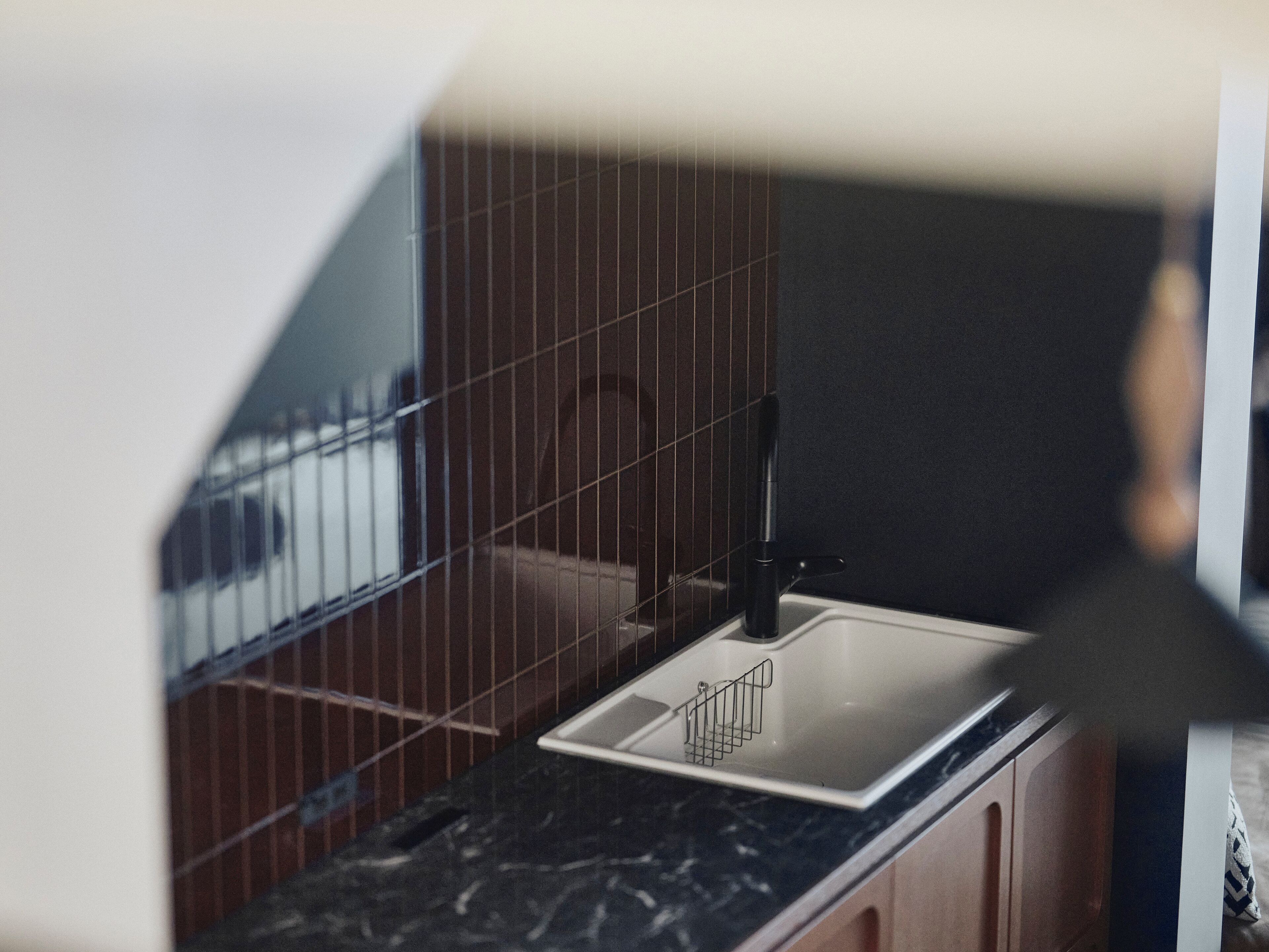 A kitchen with a sink, tiled backsplash, and wooden cabinets.
