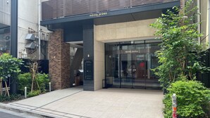 Entrada de hotel con diseño moderno, que incluye fachada de vidrio y un letrero que dice 'NOVEL WORK'.