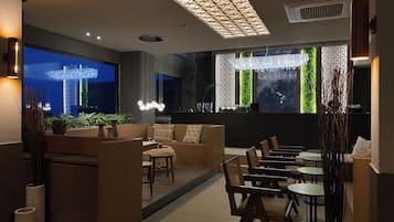 Een modern interieur met een zithoek, tafels en decoratieve verlichting.