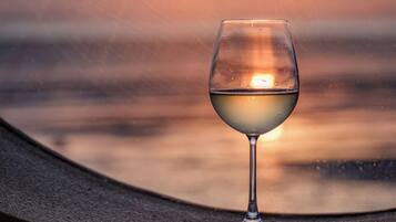 A glass of white wine on a curved ledge with a sunset in the background.