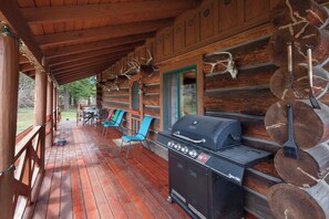 Une terrasse en bois couverte, équipée d’un barbecue et de mobilier d’extérieur.