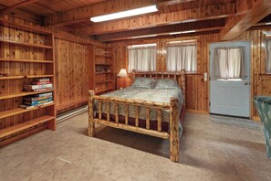 Une chambre dans une cabane en bois, avec un lit, des étagères et une porte.