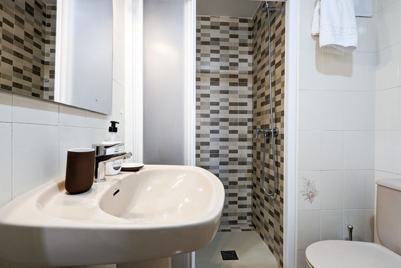 A bathroom with a sink, mirror, and shower.