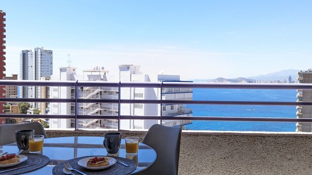 A balcony with a table set for breakfast, overlooking a cityscape and the sea. - TROPIC MAR sweet apartment (Benidorm)