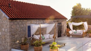 A stone building with a red-tiled roof, a glass-enclosed patio with potted plants, a wooden bench, and a canopy-covered seating area. - Villa Mar is a place of pure serenity and relaxation with its beautiful views (Orašac)