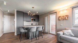 A modern kitchen with a central island, bar stools, and a unique chandelier.