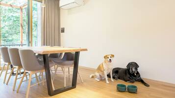 Un comedor con una mesa, sillas, dos perros y dos cuencos en el suelo.