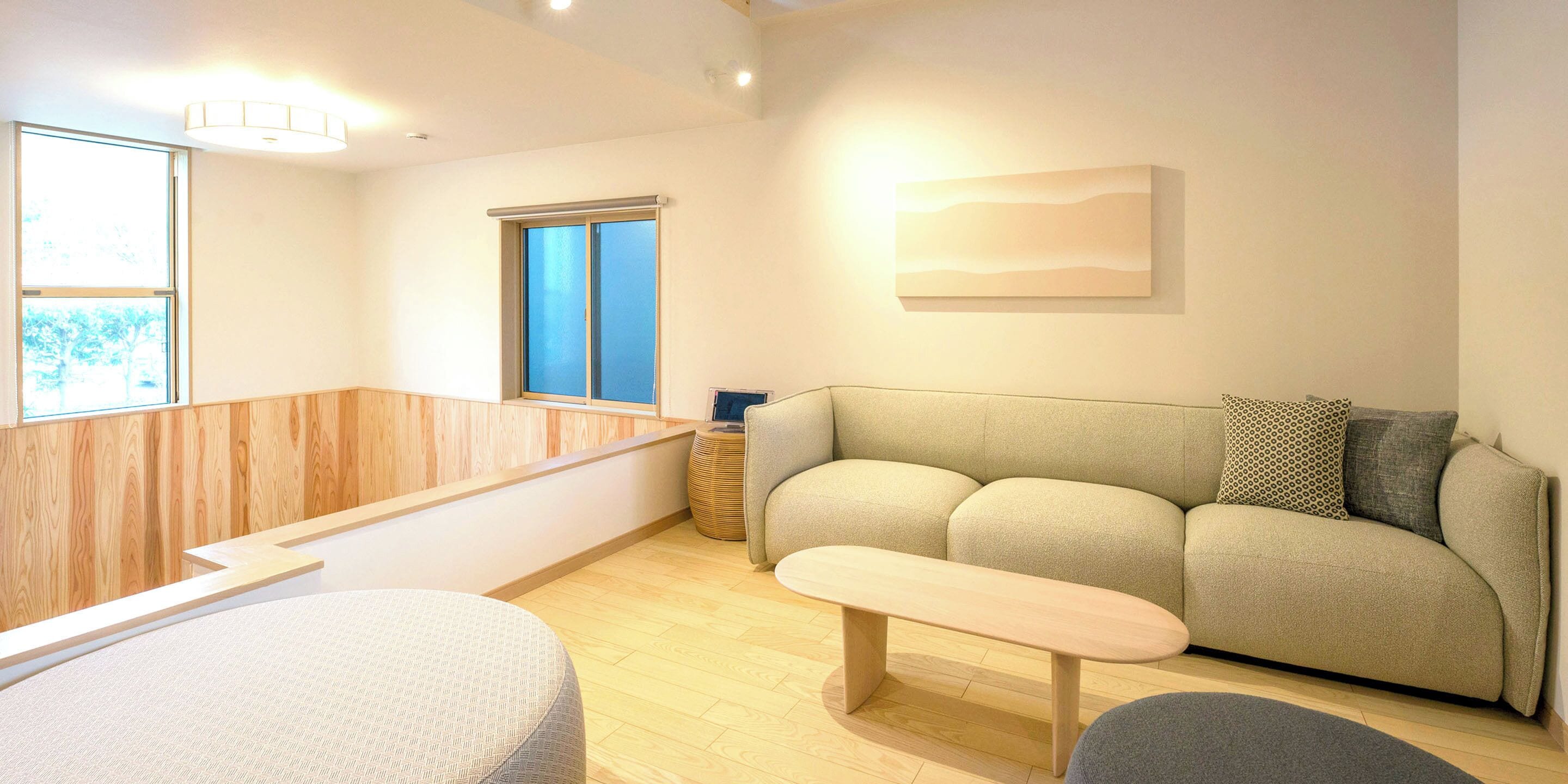 A modern living room with a sofa, a bench, and a wooden floor.