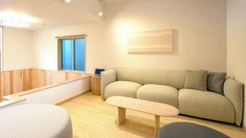 A modern living room with a sofa, a bench, and a wooden floor.