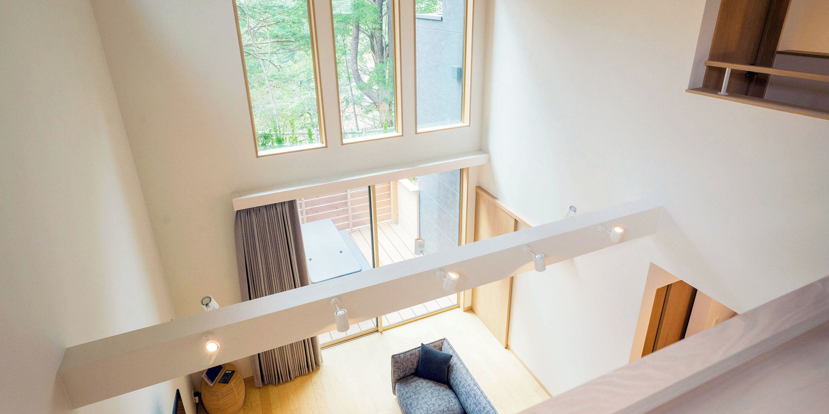 A multi-level interior with a staircase, a seating area, and large windows offering views of the outdoors.