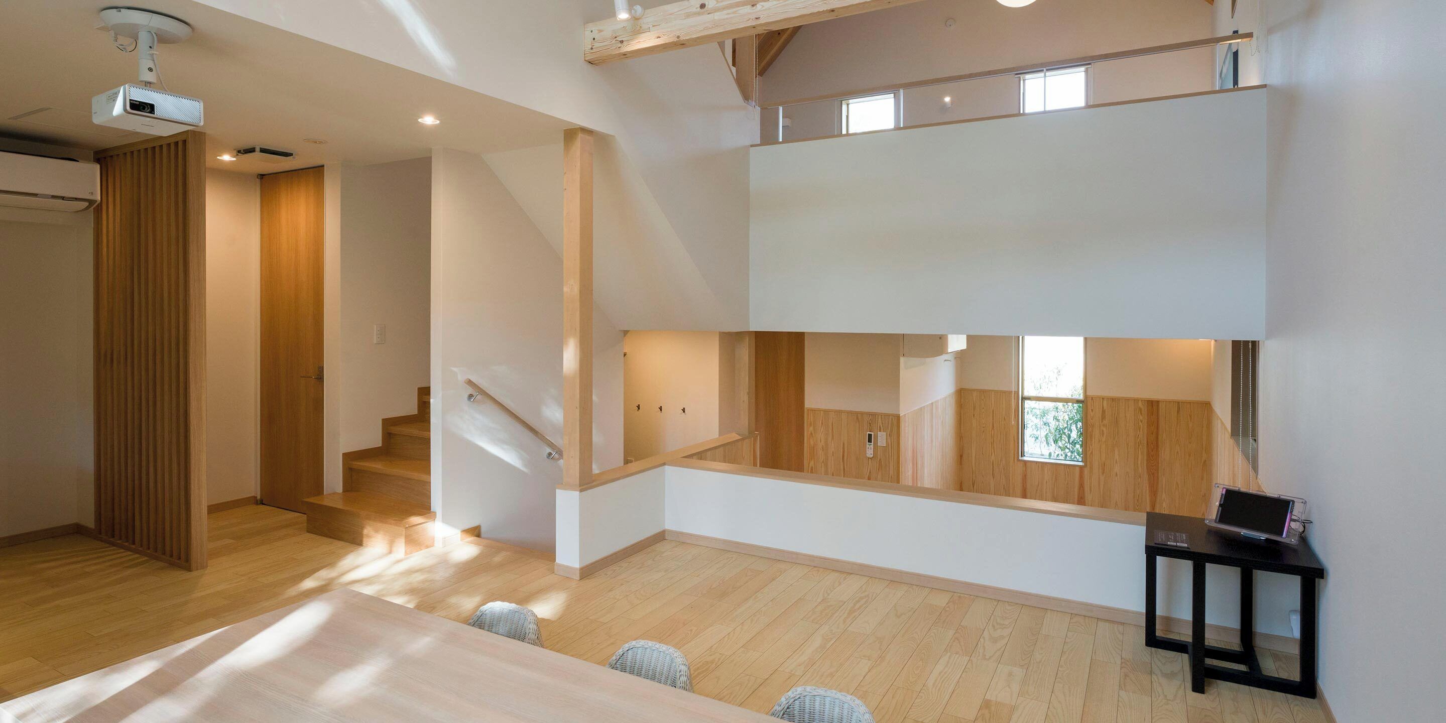 Un intérieur moderne avec un plancher en bois, un escalier et un bureau avec un ordinateur portable.