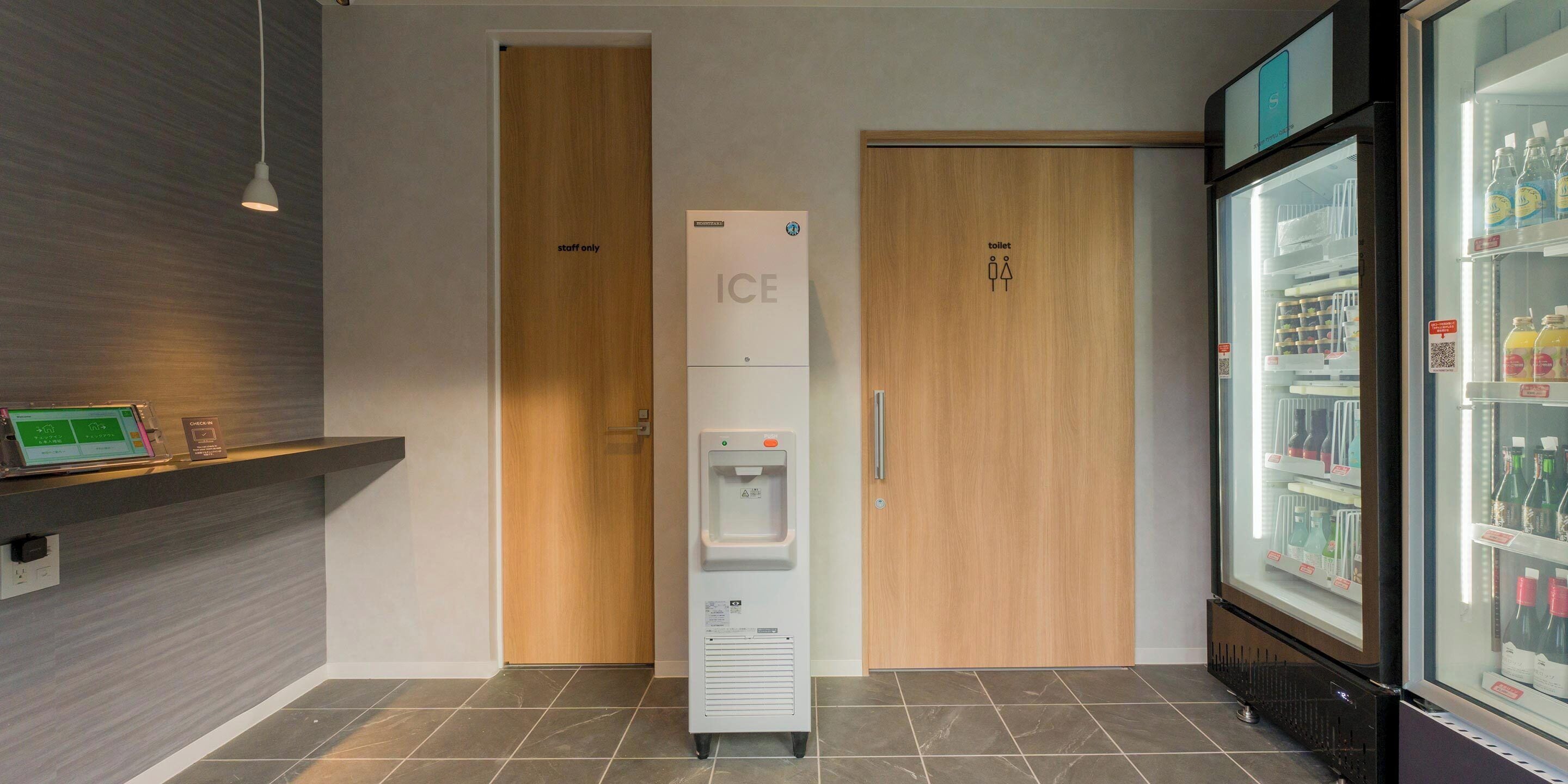 A modern restroom with a water dispenser, a refrigerated display case, and a 'staff only' door.