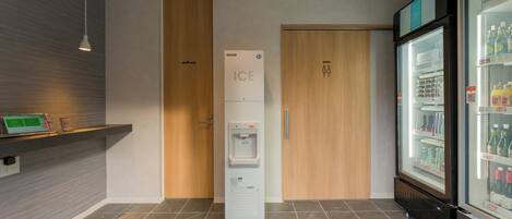 A modern restroom with a water dispenser, a refrigerated display case, and a 'staff only' door.