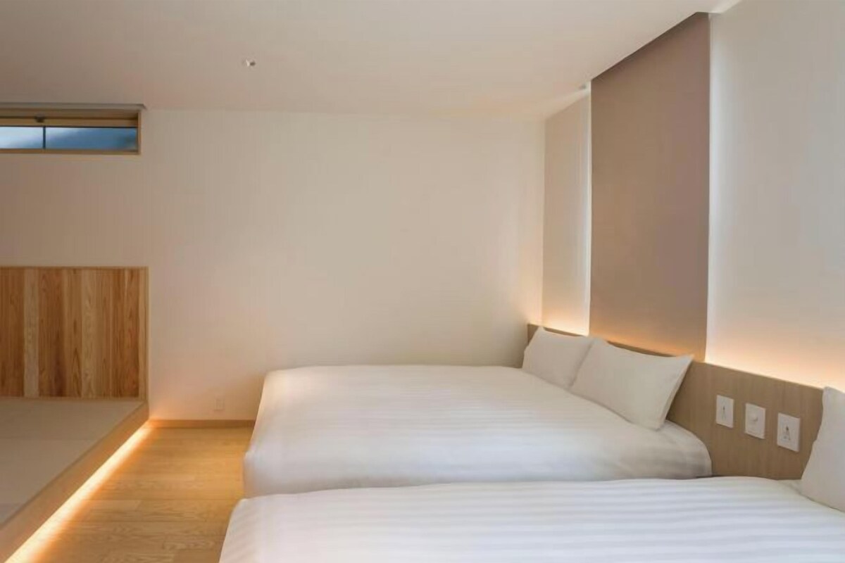 A hotel room with two beds, a wooden headboard, and a small window.