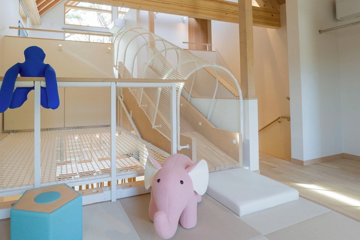 A children's play area with a slide, a climbing net, and a soft play mat.