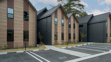 Een modern gebouw met een parkeerplaats en genummerde parkeerplaatsen.