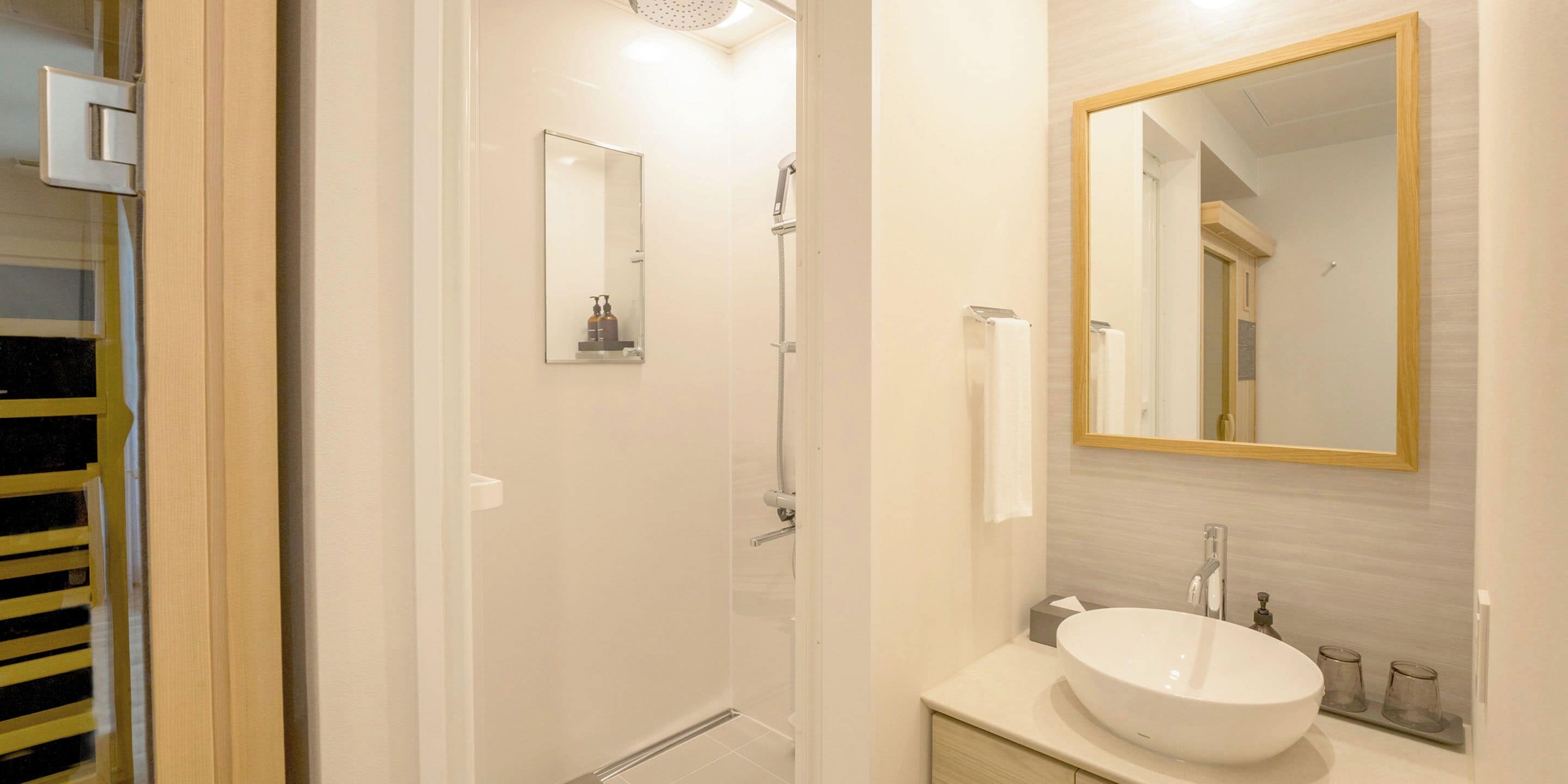 Un baño moderno con un espejo grande, un lavamanos y una ducha.