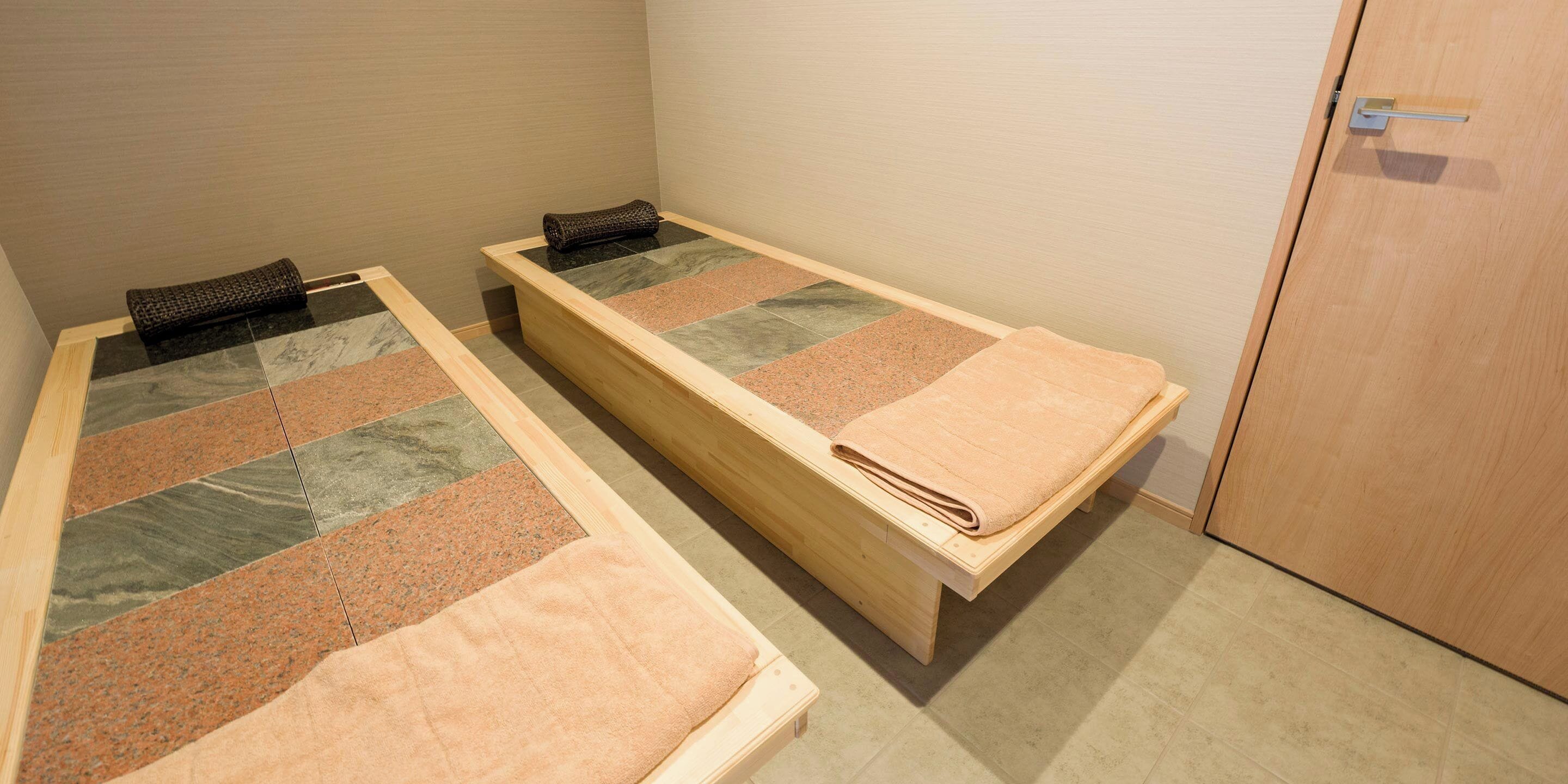 Two single beds with wooden frames and a wooden bench.