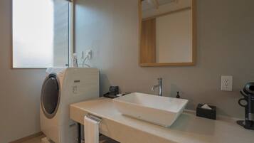A modern bathroom with a built-in washing machine, a sink with a mirror above, and a towel rack.