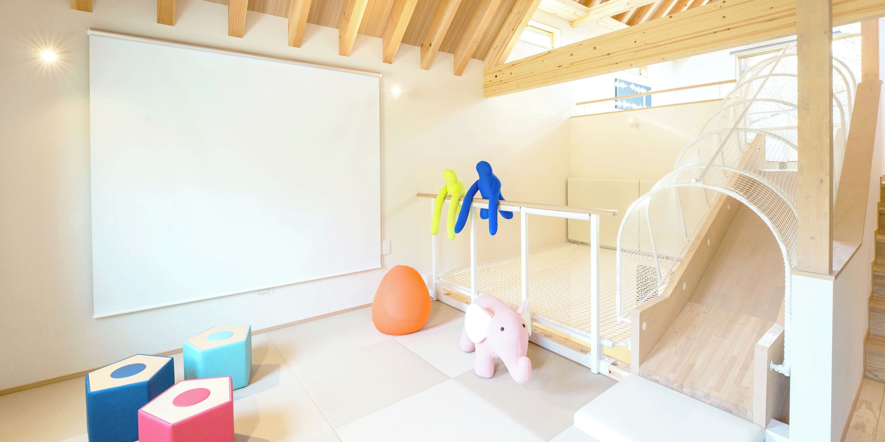 Zona de juegos infantiles con un tobogán, colchonetas blandas y juguetes coloridos.