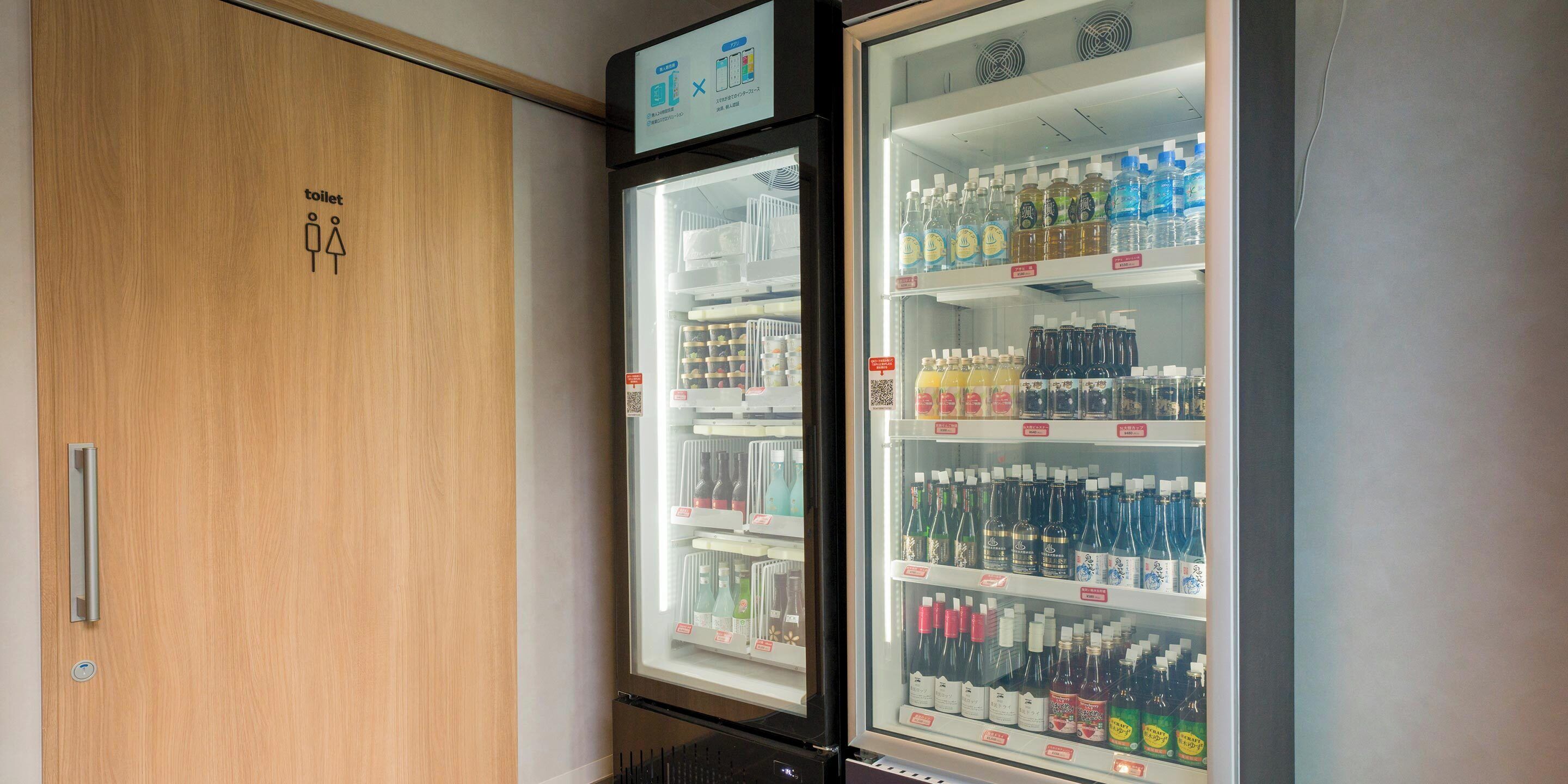 A restroom with a wooden door and a refrigerated beverage display.