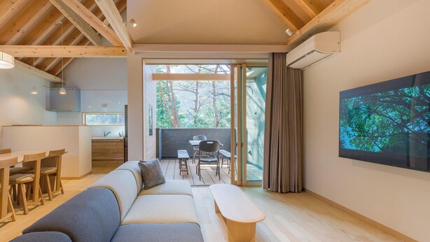 A modern living room with a sofa, dining table, and chairs. There is a kitchen area with a sink and cabinets, and a large window with curtains. - Rakuten STAY VILLA Kinugawa Riverside (Nikko)