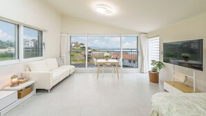 Een moderne woonkamer met een bank, een eettafel, een televisie en een balkon met uitzicht.