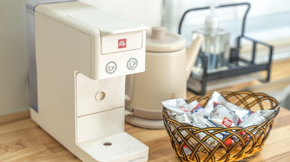 A coffee machine with a basket of coffee pods on a wooden surface. - Ganghwado Narangstay Poolvilla Pension (Incheon)