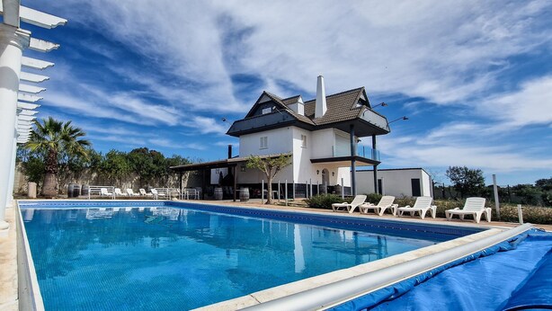 Una casa moderna con piscina, colonne bianche e una pergola.