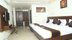 A hotel room with a large bed, a TV, a desk, and a shower area. - Park Niveda (Hyderabad)