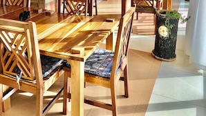 A spacious dining area with wooden tables and chairs, stone pillars, and a bar area with shelves of bottles. - The address resort (Bugala Island)